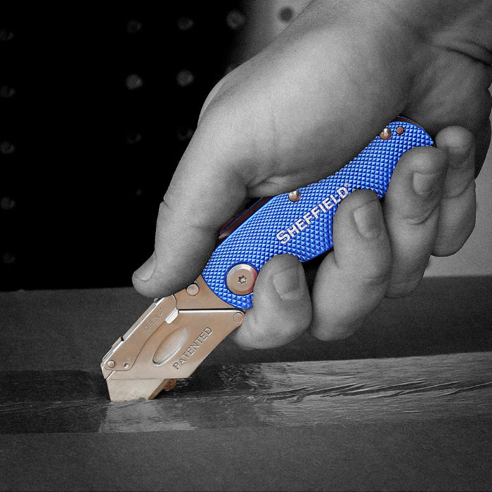 Black and white image of someone using a Sheffield utility knife saw where only the knife is colored blue.